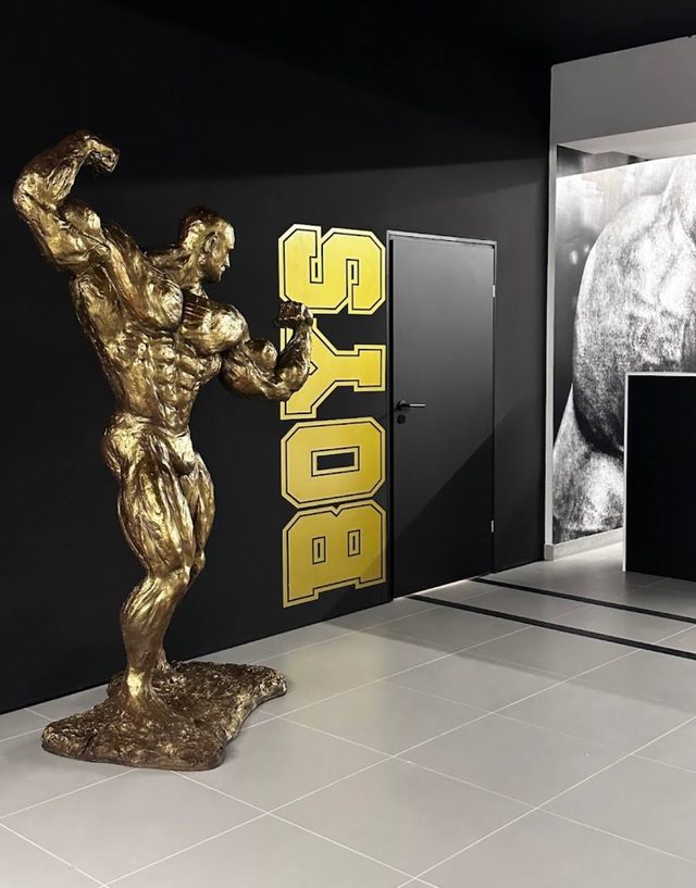 Złota figura kulturysty przy wejściu do szatni męskiej z napisem Boys